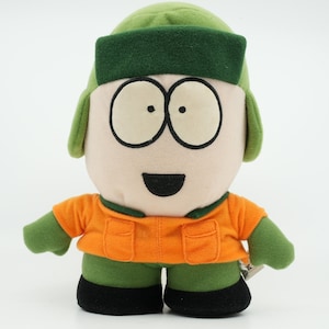 May include: Green plush toy with a brown hat and orange jacket. The toy has a smiling face with black eyes and a black mouth.