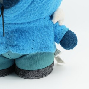 Puede incluir: Juguete de peluche azul con capucha blanca y una etiqueta negra que dice "Edici&oacute;n limitada". El juguete lleva pantalones azules con ribetes negros.