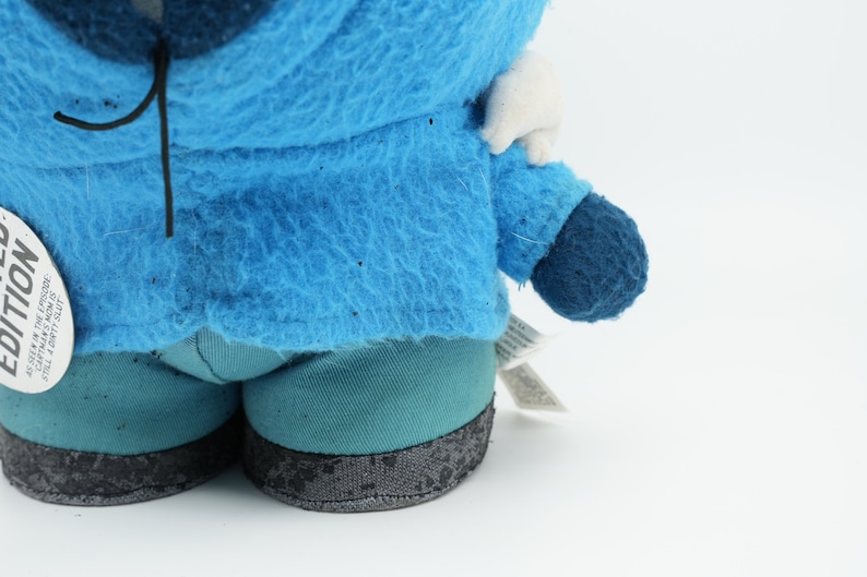 Puede incluir: Juguete de peluche azul con capucha blanca y una etiqueta negra que dice "Edici&oacute;n limitada". El juguete lleva pantalones azules con ribetes negros.