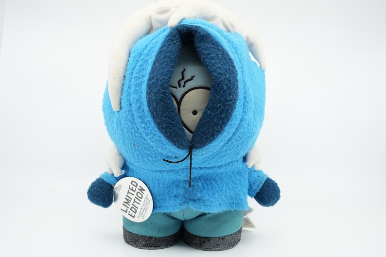 Puede incluir: Un juguete de peluche azul de un personaje que lleva una chaqueta con capucha azul con una capucha blanca. El personaje tiene una cara blanca con ojos negros y una boca negra. El juguete tiene una etiqueta que dice "Edici&oacute;n limitada".