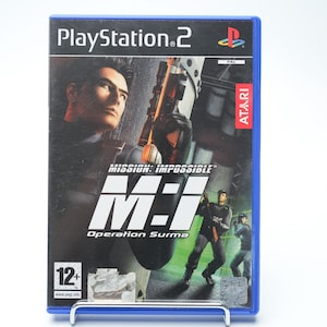 Puede incluir: Caja de juego azul de PlayStation 2 para "Mission: Impossible - Operation Surma". La portada presenta a un hombre con un arma, el título del juego y el logotipo de Atari. El juego está clasificado 12+.