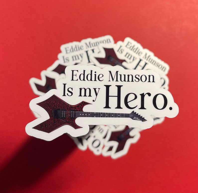 May include: A white sticker with a black and red electric guitar and the text "Eddie Munson Is my Hero."