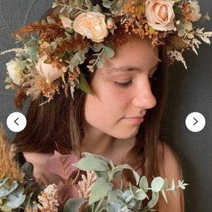 May include: A floral crown with beige roses, brown dried grasses, and eucalyptus leaves. The crown is worn by a person with brown hair.