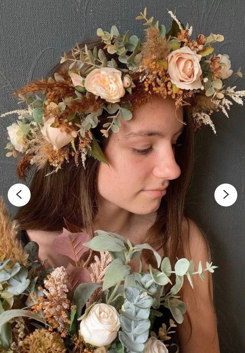 May include: A floral crown with beige roses, brown dried grasses, and eucalyptus leaves. The crown is worn by a person with brown hair.