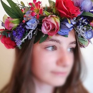 May include: A floral crown with red, pink, blue, and purple flowers. The crown is made of artificial flowers and greenery.