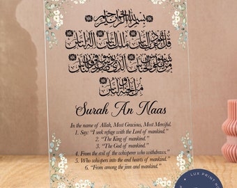 May include: A clear acrylic plaque with a floral design and Arabic calligraphy. The plaque features the text "Surah An Naas" and a translation of the Islamic prayer in English.