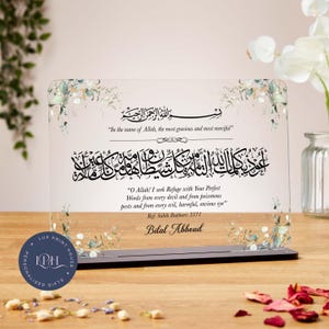 May include: A clear acrylic plaque with black Arabic calligraphy and English translation. The plaque has floral accents and a black base. Text includes "In the name of Allah" and a prayer. The plaque is a personalised gift.