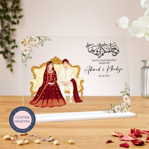 May include: A clear acrylic plaque with a custom illustration of a couple in traditional wedding attire. The plaque features a floral design and the text "And We Created You In Pairs" (Quran 78:81), "Ahmed & Khadija", and "18.10.2025".