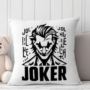 Puede incluir: Almohada blanca con una ilustraci&oacute;n en blanco y negro del Joker de Batman. La ilustraci&oacute;n incluye la palabra "JOKER" en letras grandes y el texto "JOL HU LIE LH" en letras m&aacute;s peque&ntilde;as.
