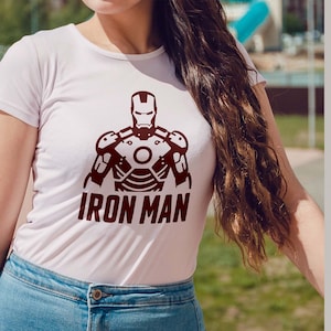 May include: White t-shirt featuring a maroon Iron Man graphic. The design includes the Iron Man helmet and armor, with the words "IRON MAN" below. The image also displays file type options: AI, SVG, EPS, DXF, and PNG.