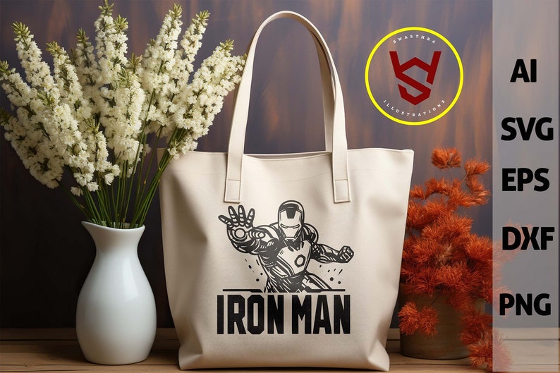 May include: Cream-colored tote bag featuring a black and white Iron Man graphic. The bag has two handles and the words "IRON MAN" printed below the character. The image also includes a logo and file type options.
