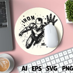 May include: Round beige mousepad featuring a black and white illustration of Iron Man in a dynamic pose, with the word "IRON MAN" in bold letters. A white computer mouse rests on the pad. The image is surrounded by a laptop, keyboard, and a cup of coffee.