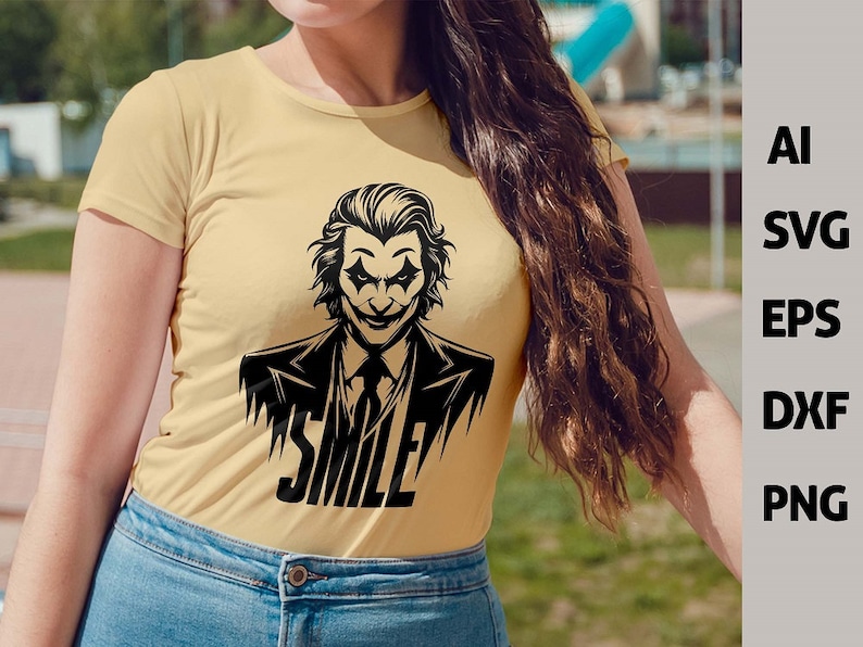 Puede incluir: Una camiseta amarilla con una ilustraci&oacute;n en blanco y negro de un personaje de Joker sonriente. El texto "SMILE" est&aacute; impreso debajo del personaje.