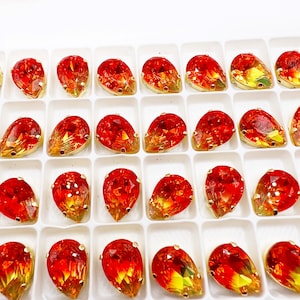 May include: A close-up of a tray of 36 teardrop-shaped rhinestones. The rhinestones are a gradient of red, orange, and yellow.