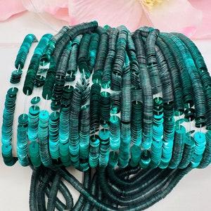 May include: A spool of teal green sequins, arranged in rows, with a shiny metallic finish.