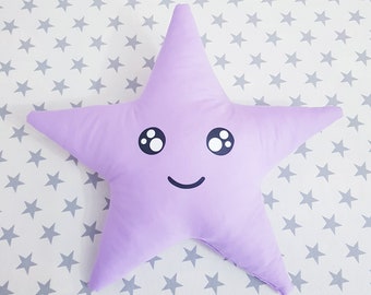 May include: A purple star-shaped pillow with a smiling face and large eyes. The pillow is on a white background with a pattern of small gray stars.