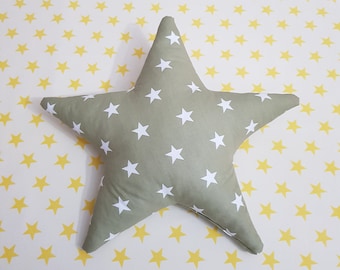 May include: A green star-shaped pillow with white stars printed on it. The pillow is on a white background with a yellow star pattern.
