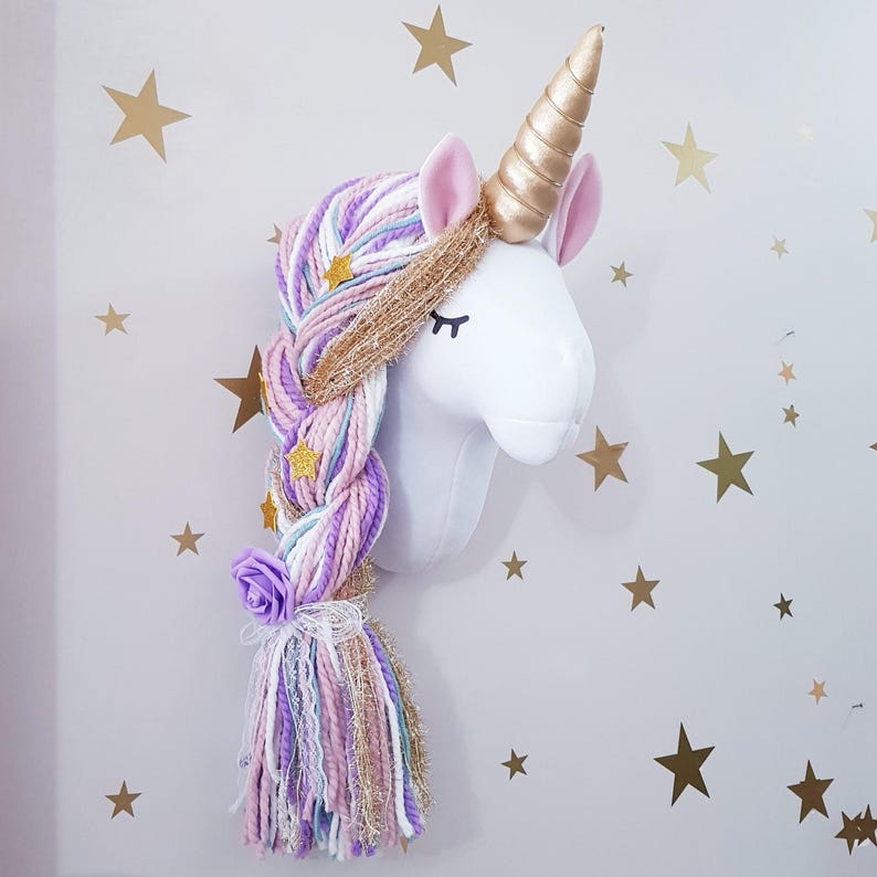 May include: A white unicorn head wall decoration with a gold horn, pink ears, and a braided mane of purple, pink, and blue yarn. The mane is decorated with gold stars and a purple rose. Gold star decals on the wall.