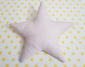 May include: A large, light pink star-shaped pillow on a white background with a yellow star pattern.