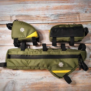 May include: Three green and yellow bike bags with black straps and zippers. The bags are on a wooden surface.