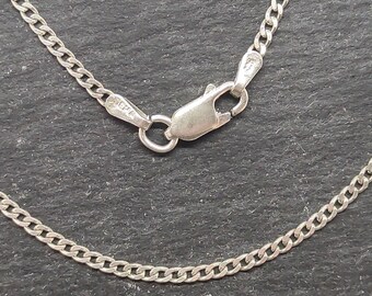 Könnte beinhalten: Eine silberne Kettenkette mit einem Karabinerverschluss. Die Kette ist im Curb-Stil mit einem flachen, rechteckigen Glied.