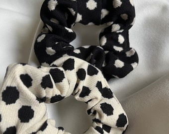 May include: Two black and white polka dot scrunchies. One scrunchie is black with white polka dots and the other is white with black polka dots.