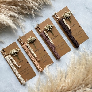 Made with 100% cotton thread, the macrame bracelet is attached to a customizable kraft card. There are flowers on the card.