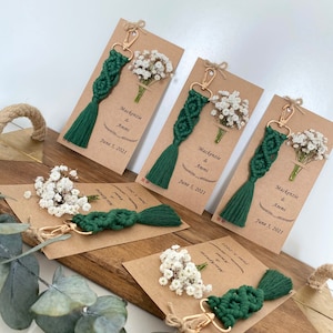 Macrame key chain knitted with cotton rope is attached to a personalized kraft card. There are white flowers on the card.
