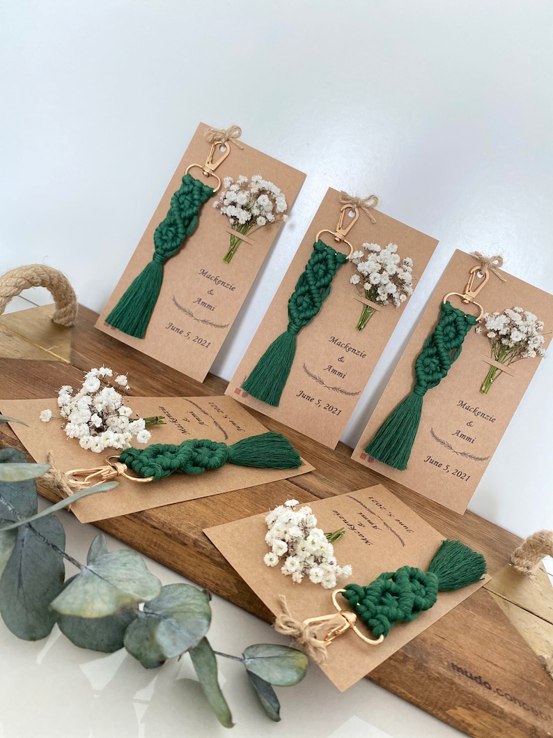 Macrame key chain knitted with cotton rope is attached to a personalized kraft card. There are white flowers on the card.