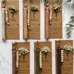 Made with 100% cotton thread, the macrame bracelet is attached to a customizable kraft card. There are flowers on the card.