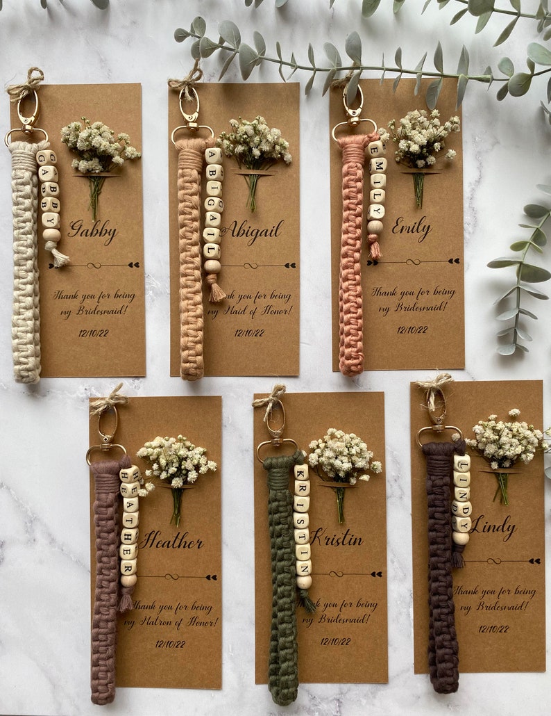 Made with 100% cotton thread, the macrame bracelet is attached to a customizable kraft card. There are flowers on the card.