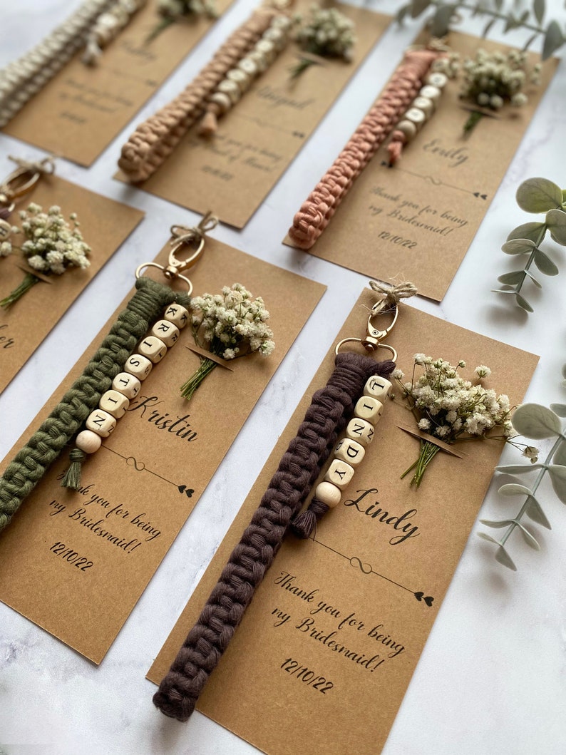 Made with 100% cotton thread, the macrame bracelet is attached to a customizable kraft card. There are flowers on the card.