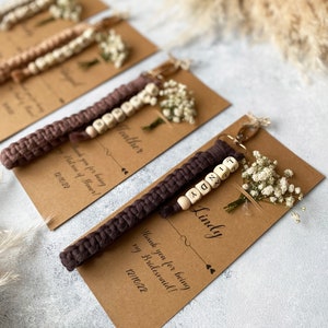 Made with 100% cotton thread, the macrame bracelet is attached to a customizable kraft card. There are flowers on the card.