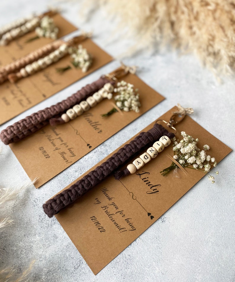 Made with 100% cotton thread, the macrame bracelet is attached to a customizable kraft card. There are flowers on the card.