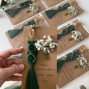 Macrame key chain knitted with cotton rope is attached to a personalized kraft card. There are white flowers on the card.
