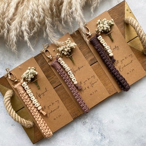 Made with 100% cotton thread, the macrame bracelet is attached to a customizable kraft card. There are flowers on the card.