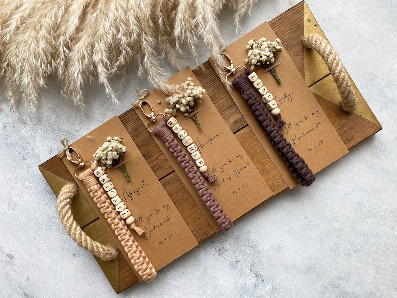 Made with 100% cotton thread, the macrame bracelet is attached to a customizable kraft card. There are flowers on the card.
