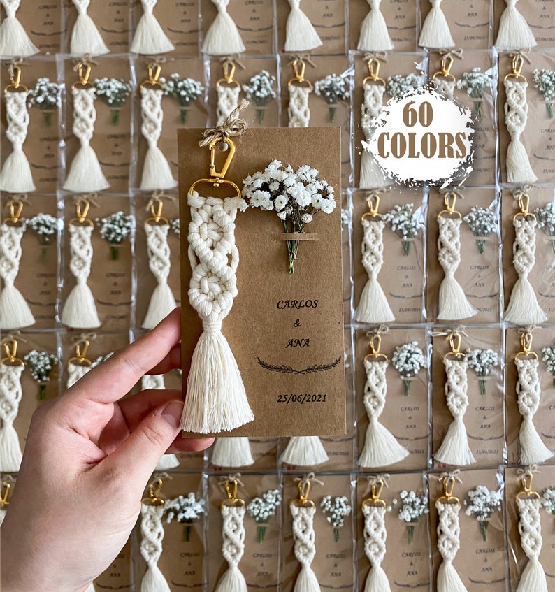 Macrame key chain knitted with cotton rope is attached to a personalized kraft card. There are white flowers on the card.