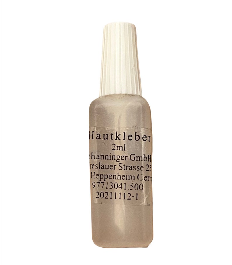 May include: A clear plastic bottle with a white cap labeled "Hautkleber 2ml" and contains a clear liquid. The bottle also has the text "Hanninger GmbH, reslauer Strasse 25, Heppenheim, Germany, 97713041.500, 20211112-1".