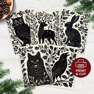May include: A collection of five black and white art prints featuring woodland animals: an owl, deer, rabbit, wolf, and raven. Each animal is surrounded by botanical illustrations. The prints are on a cream-colored background. A red circle with the text "PRINT & CUT" is visible.