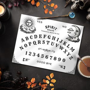 May include: A white spirit board with black lettering, illustrations of the sun and moon, and the text "Spirit Board Communicate Beyond the Veil." The board is surrounded by candles, a pumpkin, and a planchette.