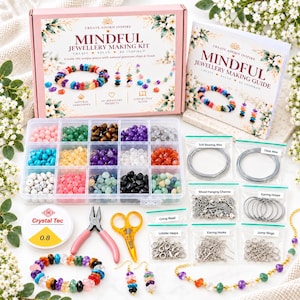 Może przedstawiać: Zestaw do tworzenia biżuterii Mindful z pudełkiem i instrukcją, przezroczysty plastikowy organizer z piętnastoma przegródkami wypełnionymi kolorowymi koralikami z kamieni szlachetnych, drutami, zawieszkami, kolczykami, haczykami, kółeczkami, zaciskami, zapięciami, szczypcami, nożyczkami i sznurkiem Crystal Tec 0.8.