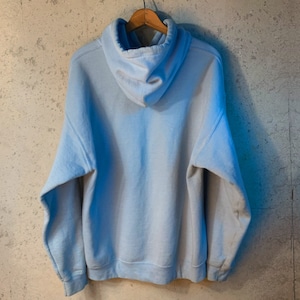 May include: A light blue hooded sweatshirt hanging on a wooden hanger against a textured grey wall.