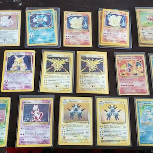 May include: A collection of 15 Pokemon trading cards featuring various characters, including Pikachu, Charizard, and Blastoise. The cards are in various colors, including yellow, blue, red, and green. The cards are in good condition and have been well-preserved.