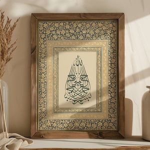 Può includere: Una stampa incorniciata con un bordo a motivi dorati e blu. La stampa presenta un design di calligrafia araba verde su uno sfondo crema.