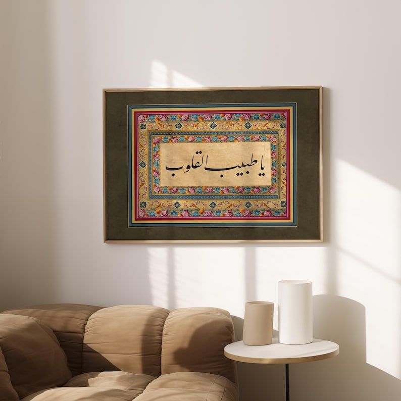 May include: A framed print of Islamic calligraphy in black ink on a gold background. The calligraphy is surrounded by a colorful floral border with intricate details. The frame is dark green.