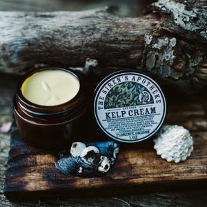 Może przedstawiać: Mały słoiczek z jasnoż&oacute;łtym kremem i brązową pokrywką. Słoiczek jest oznaczony etykietą "The Siren's Apotheke Est. 2024 Kelp Cream 1 oz Florence, Oregon".