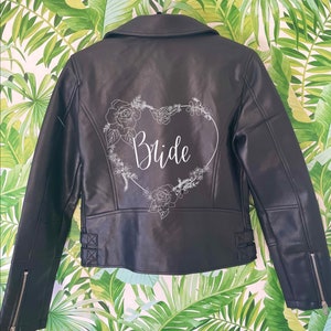 May include: Black leather jacket with a white floral design and the word "Bride" in a heart shape on the back.