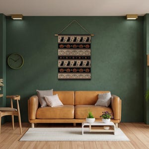 Halloween tapestry with black cats, pumpkins, and ghosts above a leather sofa.