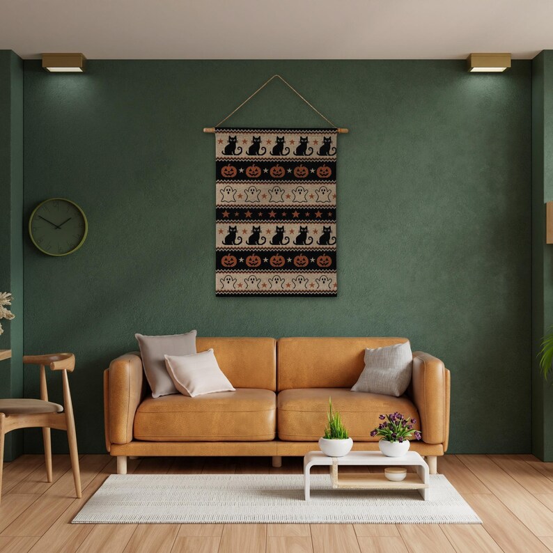 Halloween tapestry with black cats, pumpkins, and ghosts above a leather sofa.